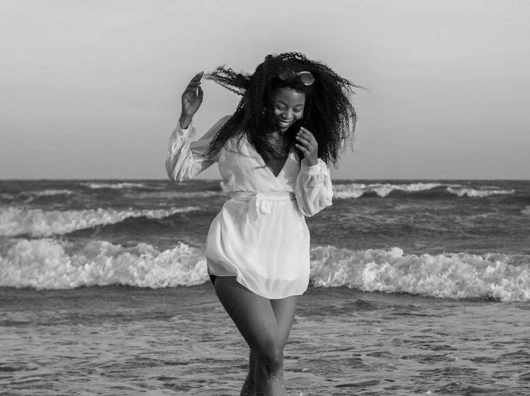 woman in white dress shirt standing on seashore during daytime