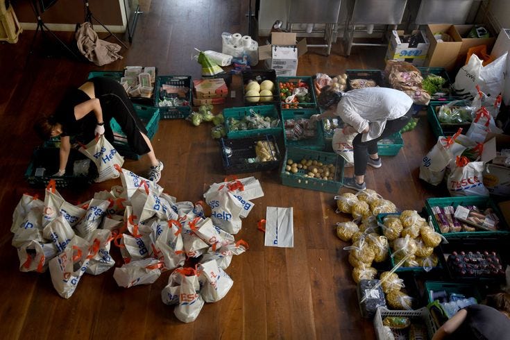 This may contain: two people picking up bags of food on the floor