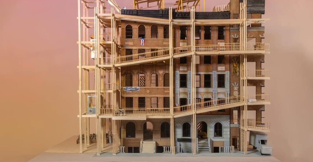 A photo of the side of an architectural model of a building. It features large exterior ramps that track alongside many windows.