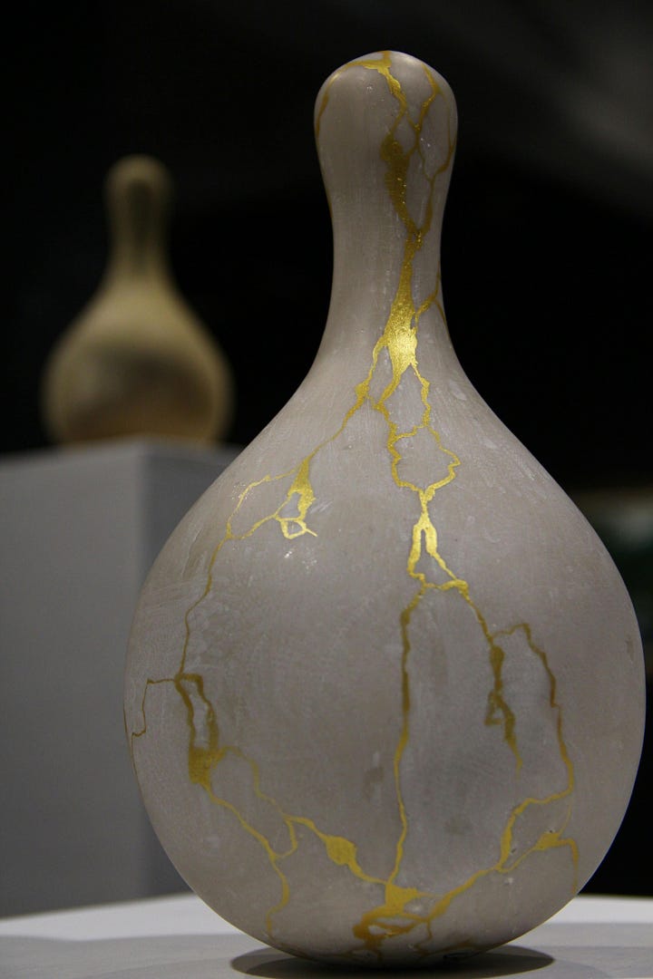 A gracefully shaped ceramic vase with delicate golden Kintsugi repairs running across its surface, illustrating the beauty and value found in accepting and celebrating flaws.A ceramic plate repaired with Kintsugi, showing prominent golden lines highlighting its cracks, symbolizing how embracing imperfections can add beauty and strength.