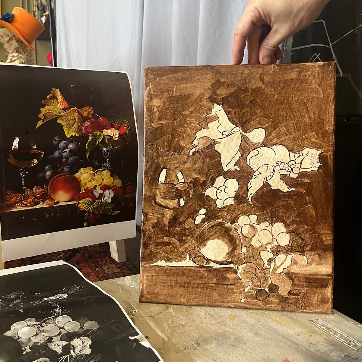 Colour print out of the still life painting alongside a canvas of the same still life in shades of brown.