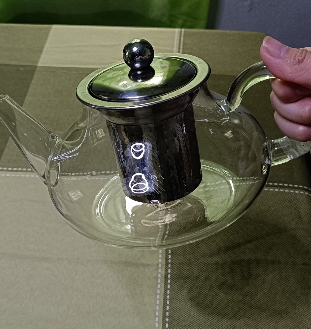 A glass teapot being held up