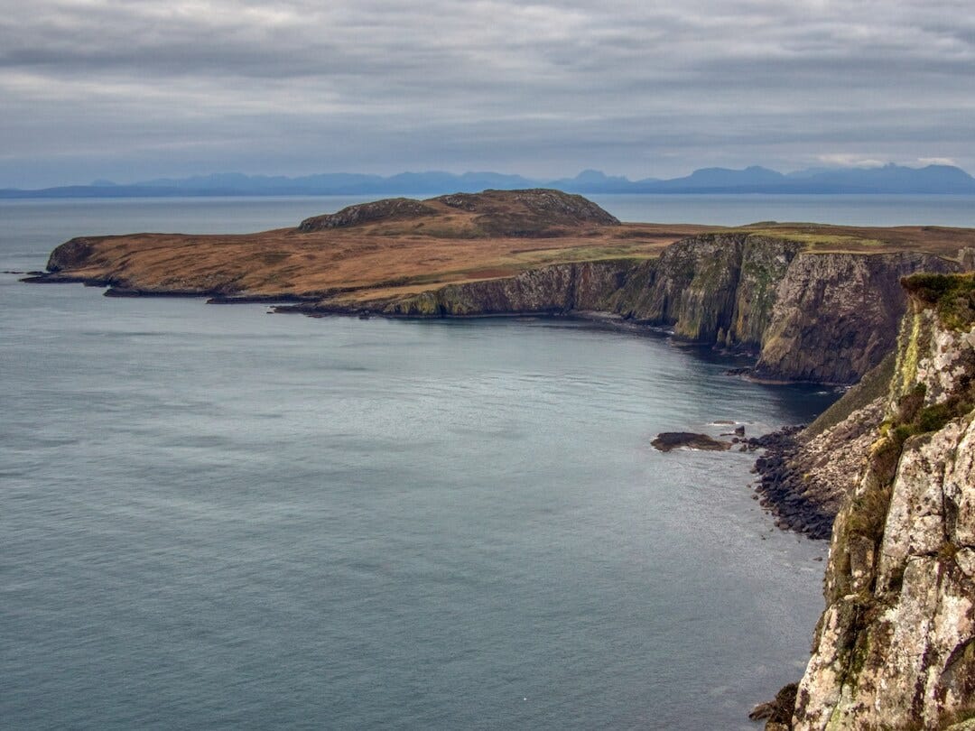 A peninsula of rock with cliffs surrounded by sea