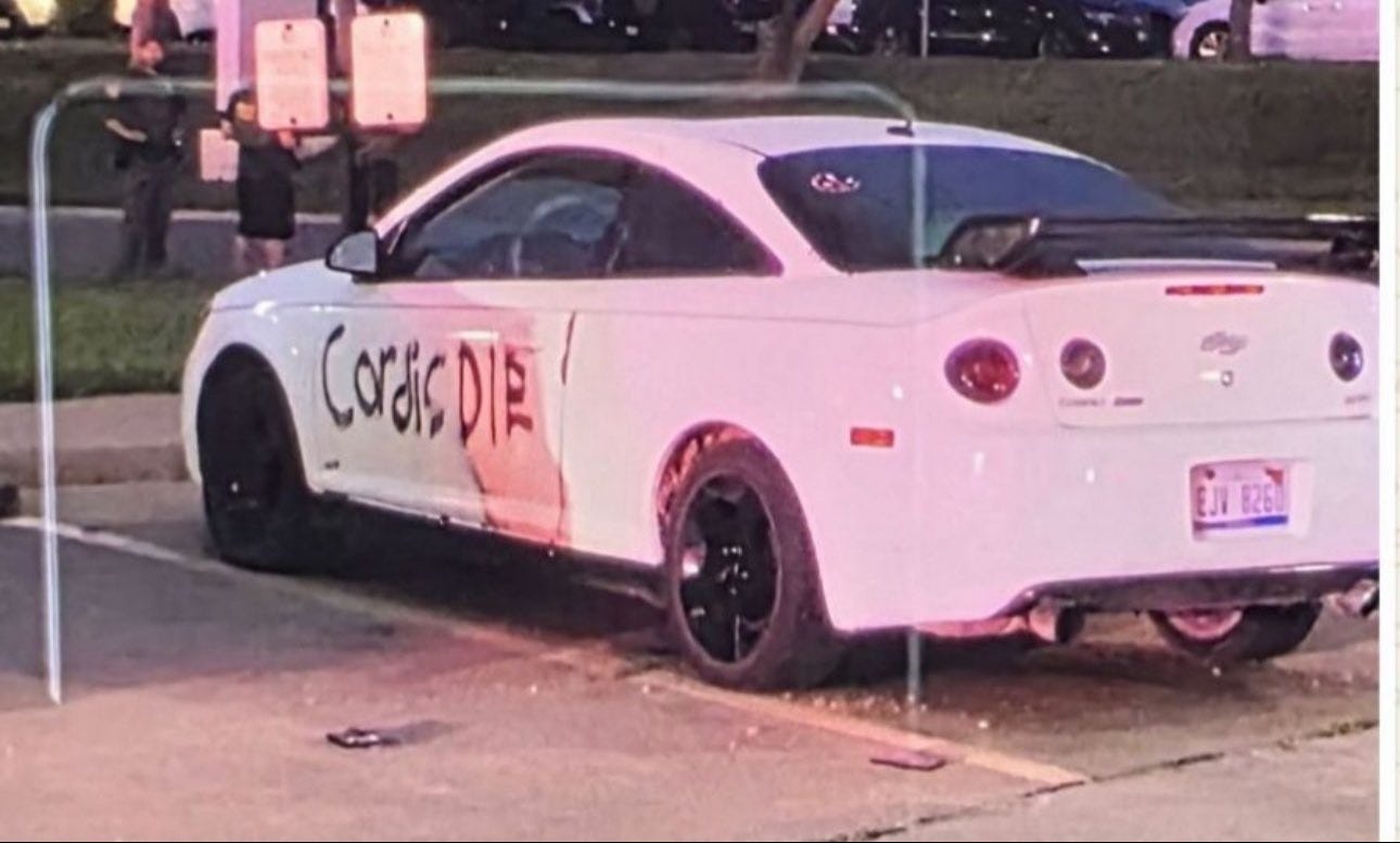The suspect's car - with the words "Cordis Die" spray painted on its door was found parked outside the ambush scene. The suspect's car - with the words "Cordis Die" spray painted on its door was found parked outside the ambush scene.