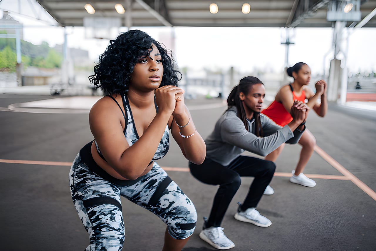 3 people squatting in an outdoor workout class