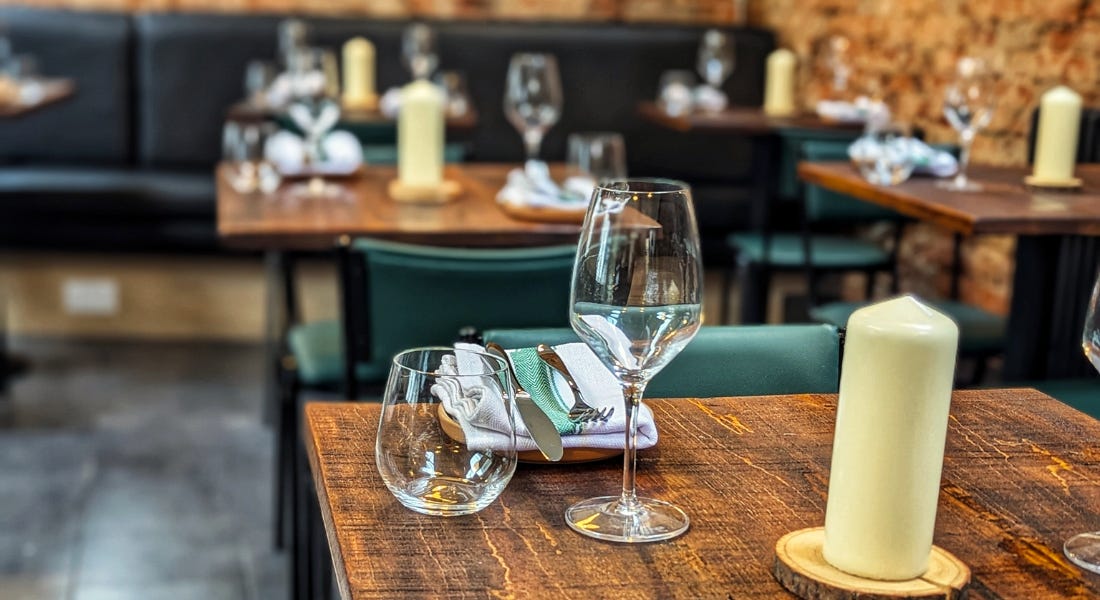 A table with glasses and candles on top of it, and matching tables behind it A table with glasses and candles on top of it, and matching tables behind it