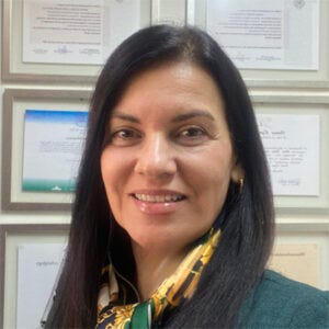Mulher de cabelo castanho médio, de blusa social e cachecol. Ela sorri para a foto. Mulher de cabelo castanho médio, de blusa social e cachecol. Ela sorri para a foto.