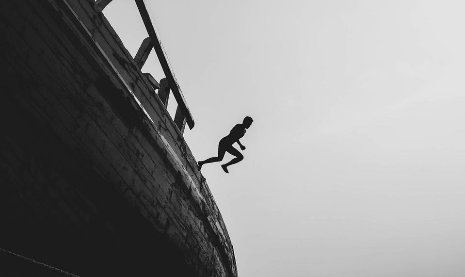 A man jumping off a boat into the sea