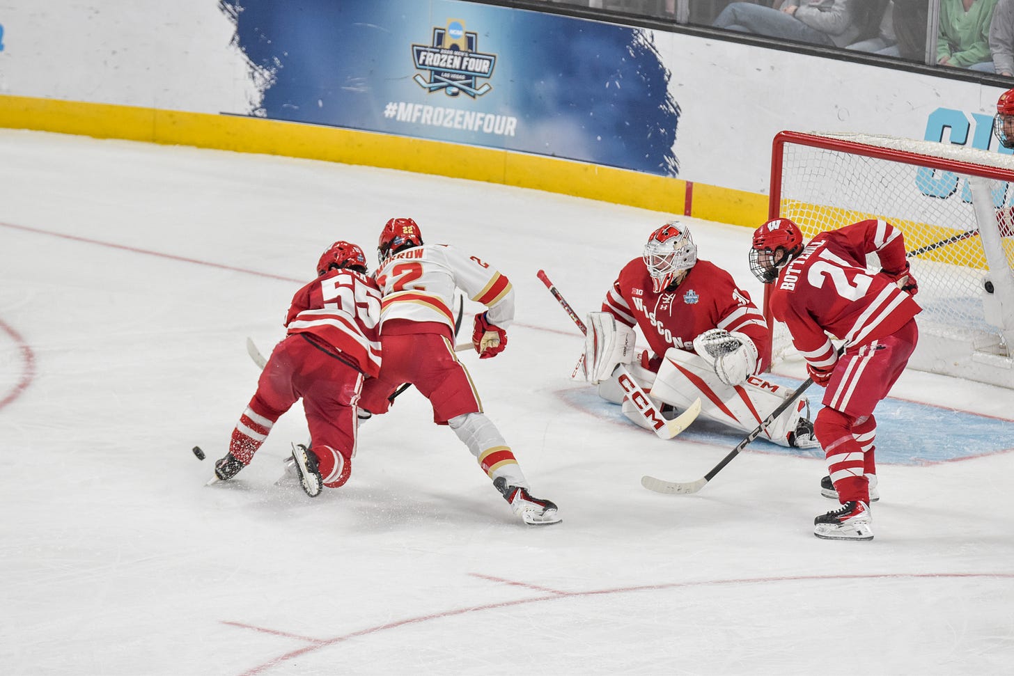 Wisconsin Badgers forward Oliver Tulk defends Denvers Brendan McMorrow while puck sits to their left in front of goal.