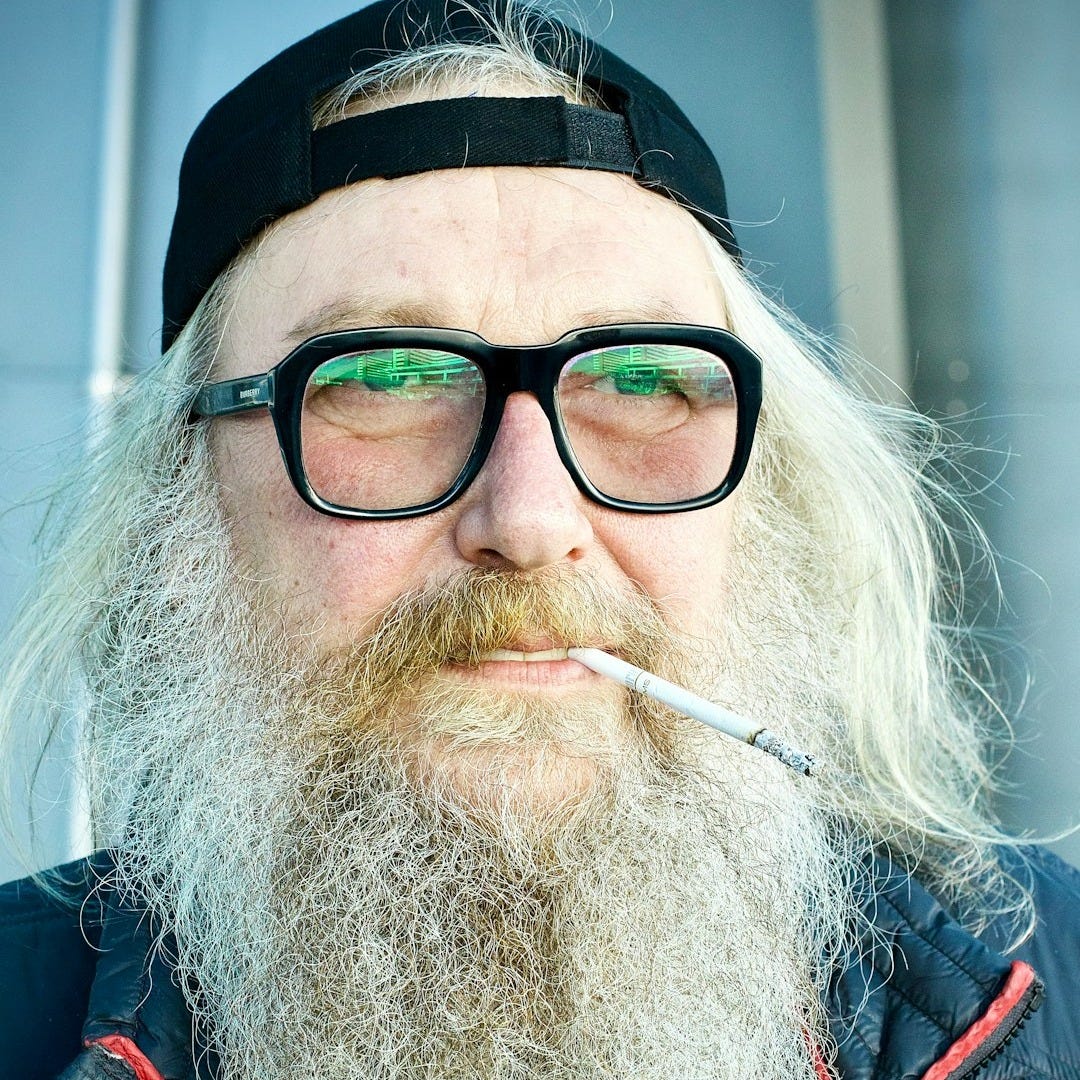 Man with a long beard smoking a cigarette.