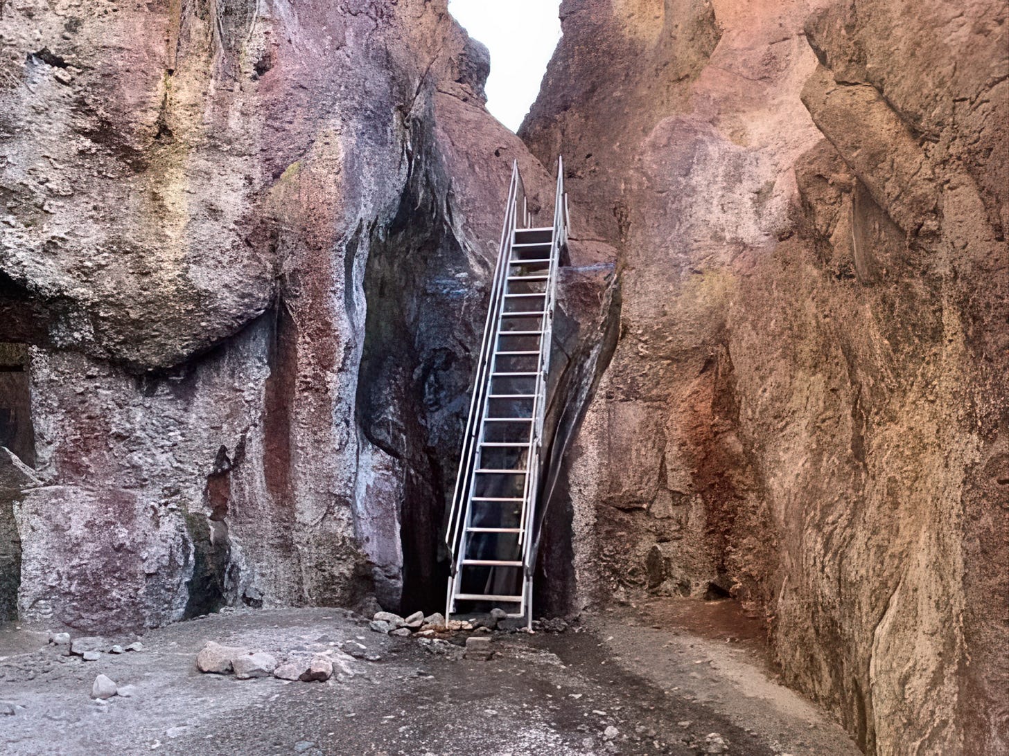 A metal ladder leans against a steep rock face inside Arizona Hot Springs canyon, providing access between the lower canyon and the upper hot spring pools.