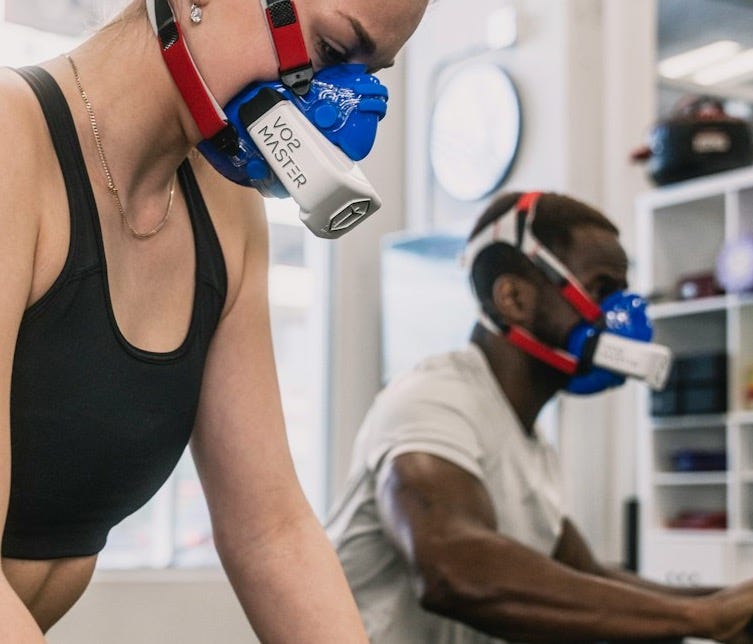 a woman wearing a gas mask while riding a stationary bike