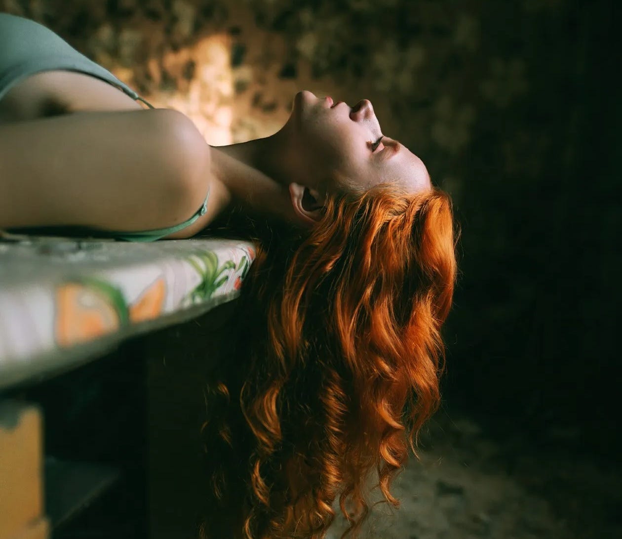 A gorgeous woman lying on her back with her long red hair hanging down close to the floor A gorgeous woman lying on her back with her long red hair hanging down close to the floor