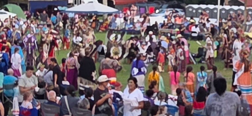 Native Americans in a dance circle with onlookers
