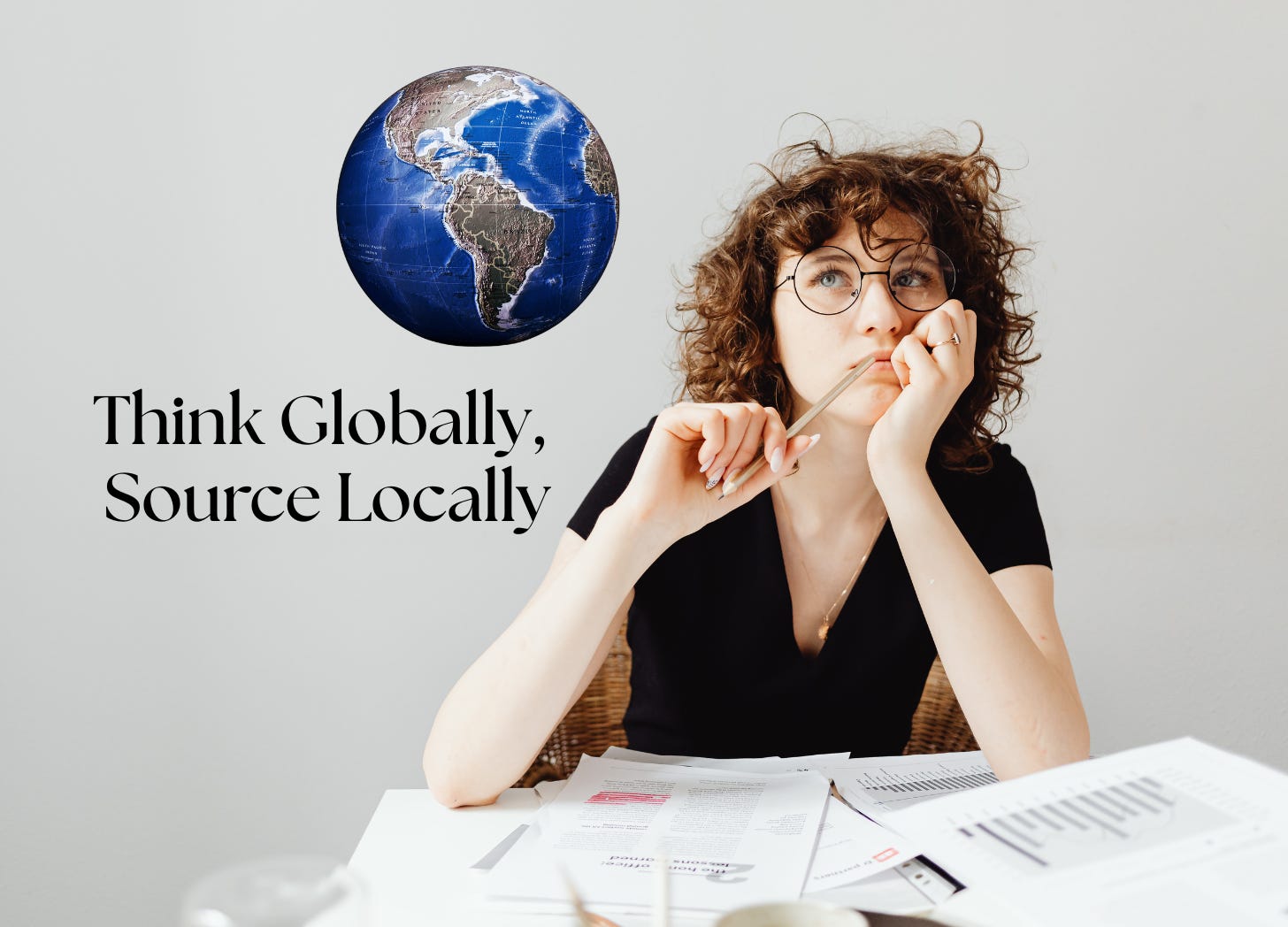 A young woman sitting at a desk. She has round wire glasses and curly hair. She is chewing on a pen and looking up to the side where I have awkwardly placed a globe. Hey, I'm a writer. Text reads: Think globally, source locally. Also, I suck at titles. 