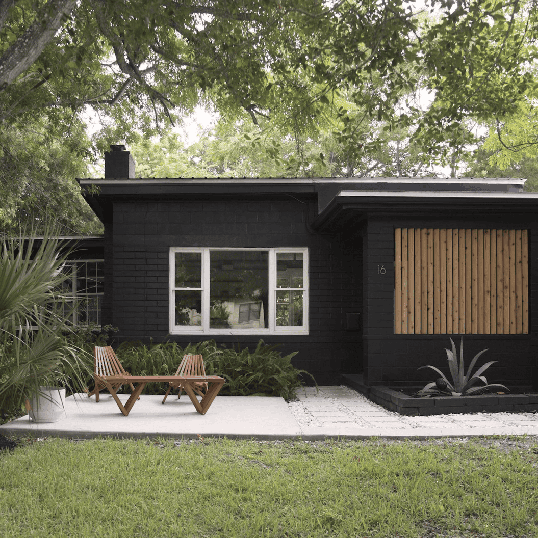 A large lawn in front of a house with a black exterior.