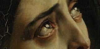 Detail of the upper half of a woman's face featuring, eyes, eyebrows, cheekbones, nose and glabella. Her gaze is turned fearfully upwards and her eyes are filled with tears.