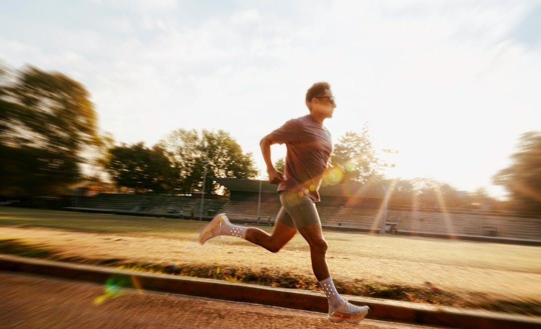 Man running on track during sunrise with lens flare. Man running on track during sunrise with lens flare.