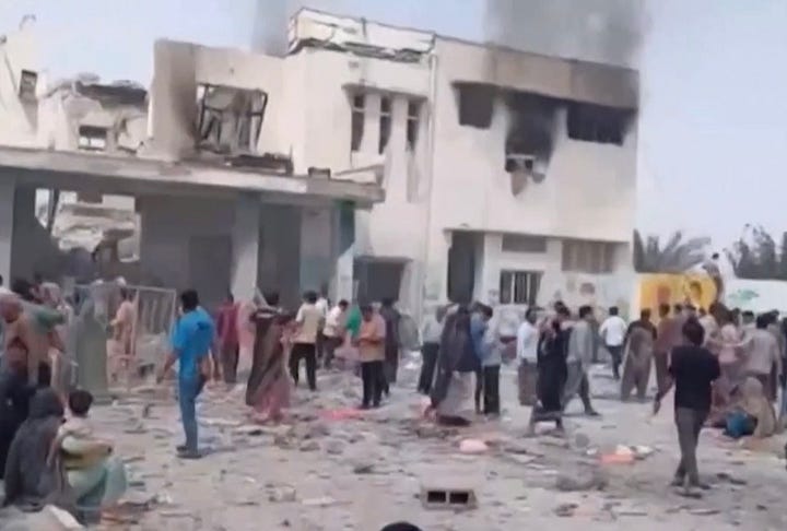 Woman in a white hijab holding up a picture of two school children, also wearing white hijabs, with a uniform of a green lab coat length dress with matching green pants underneath.  Photo #2- White building with plumes of smoke coming out of the windows of the second floor.  The left side of the second floor’s roof has been blown off.  People in various colors of dress are milling about in front of the building, with pieces of cement and debris all around them. 
