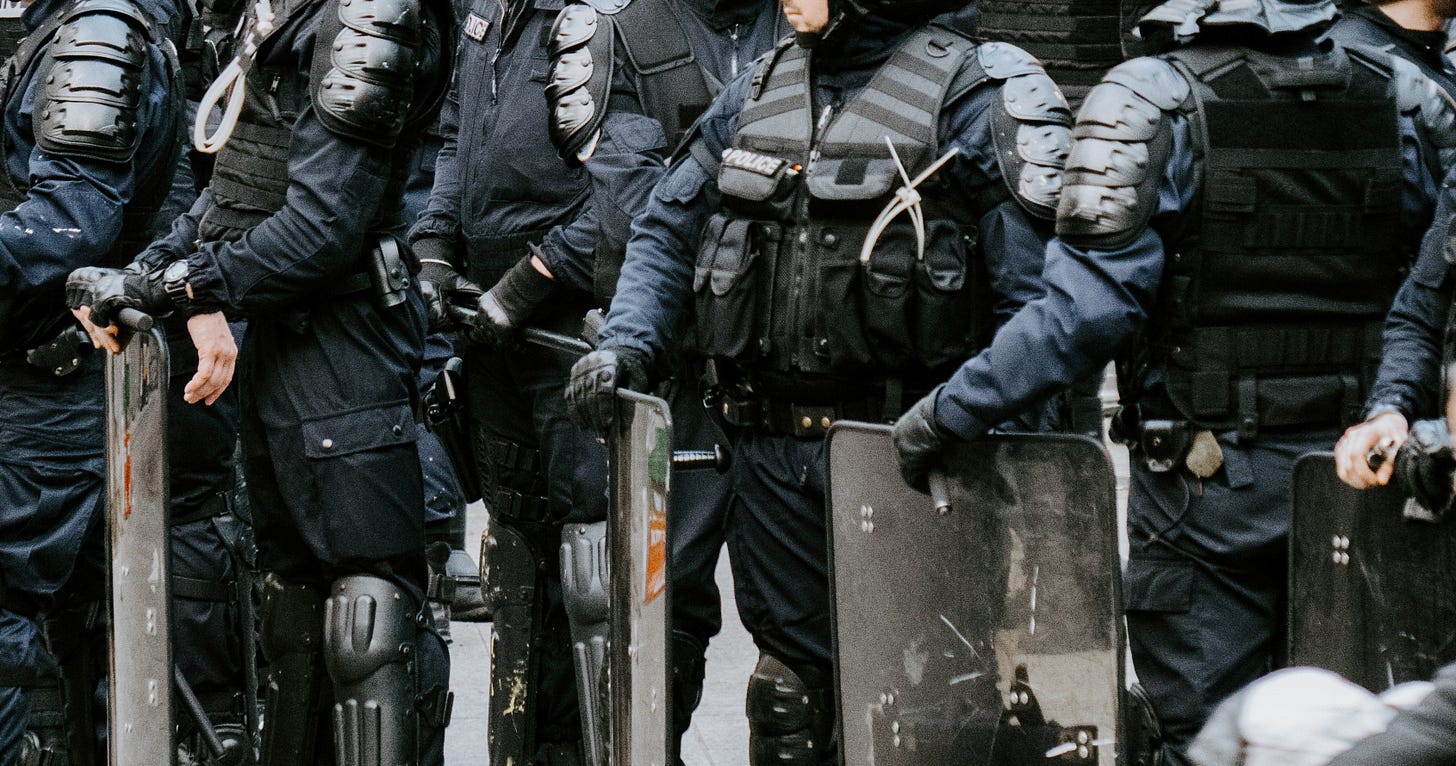 A row of riot police holding shields. A row of riot police holding shields.