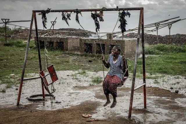 Mulher sentada em um balanço em ambiente aberto, em dia de chuva