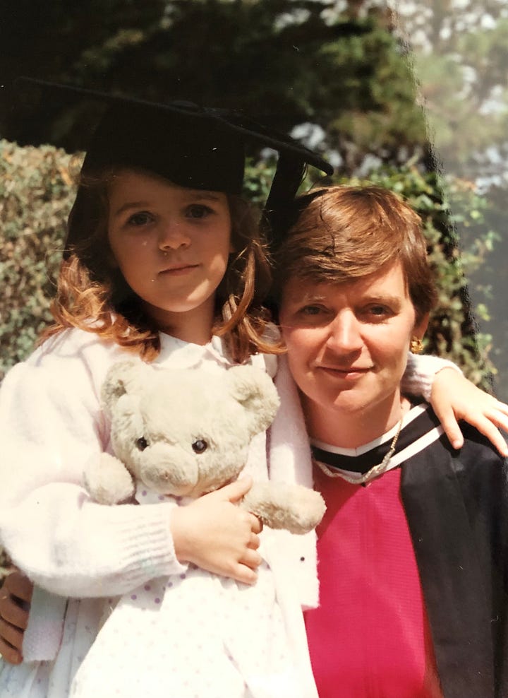 A woman in a cap and gown and a small girl in a mortar board