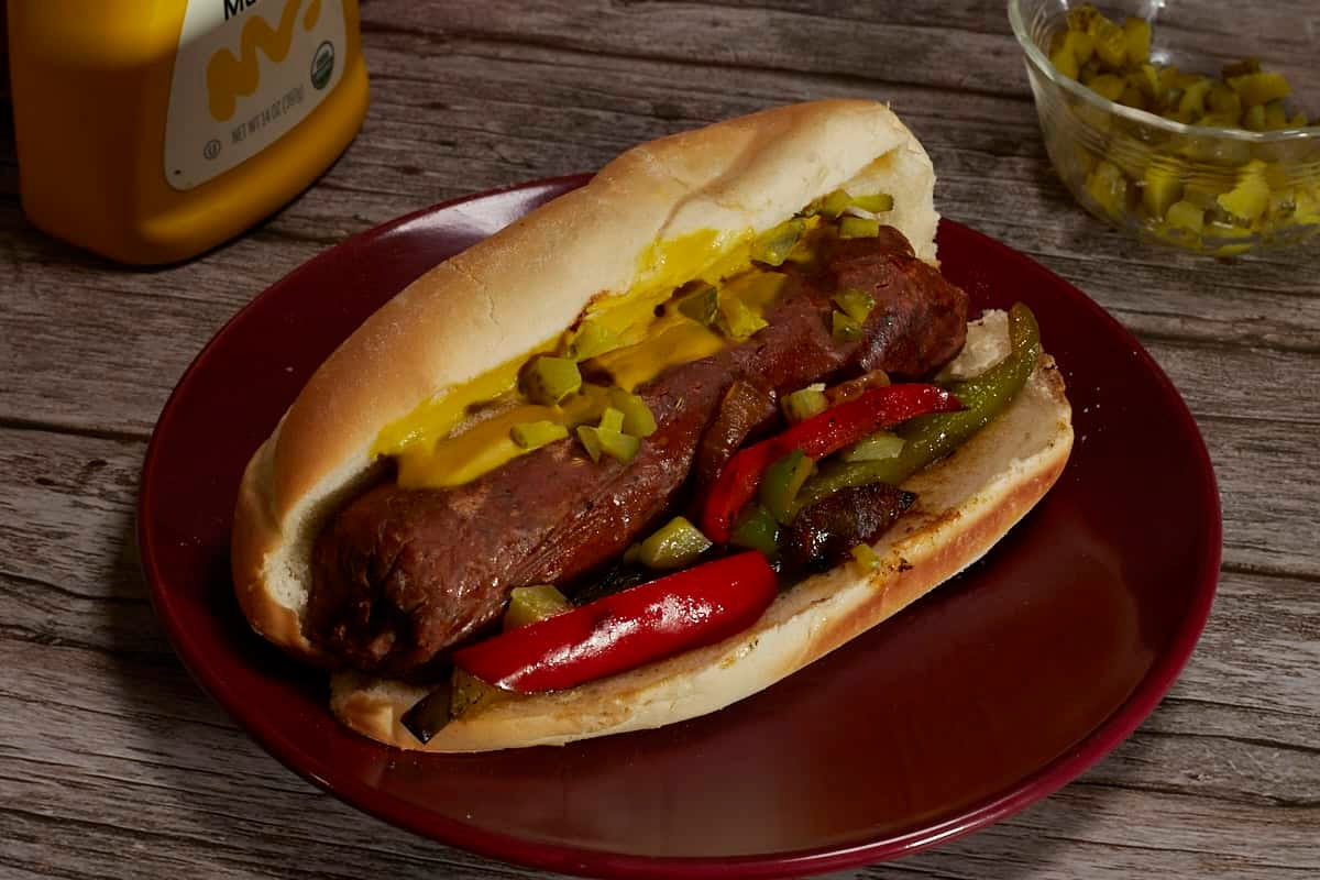 vegan Italian sausage on a bun with grilled onions and peppers
