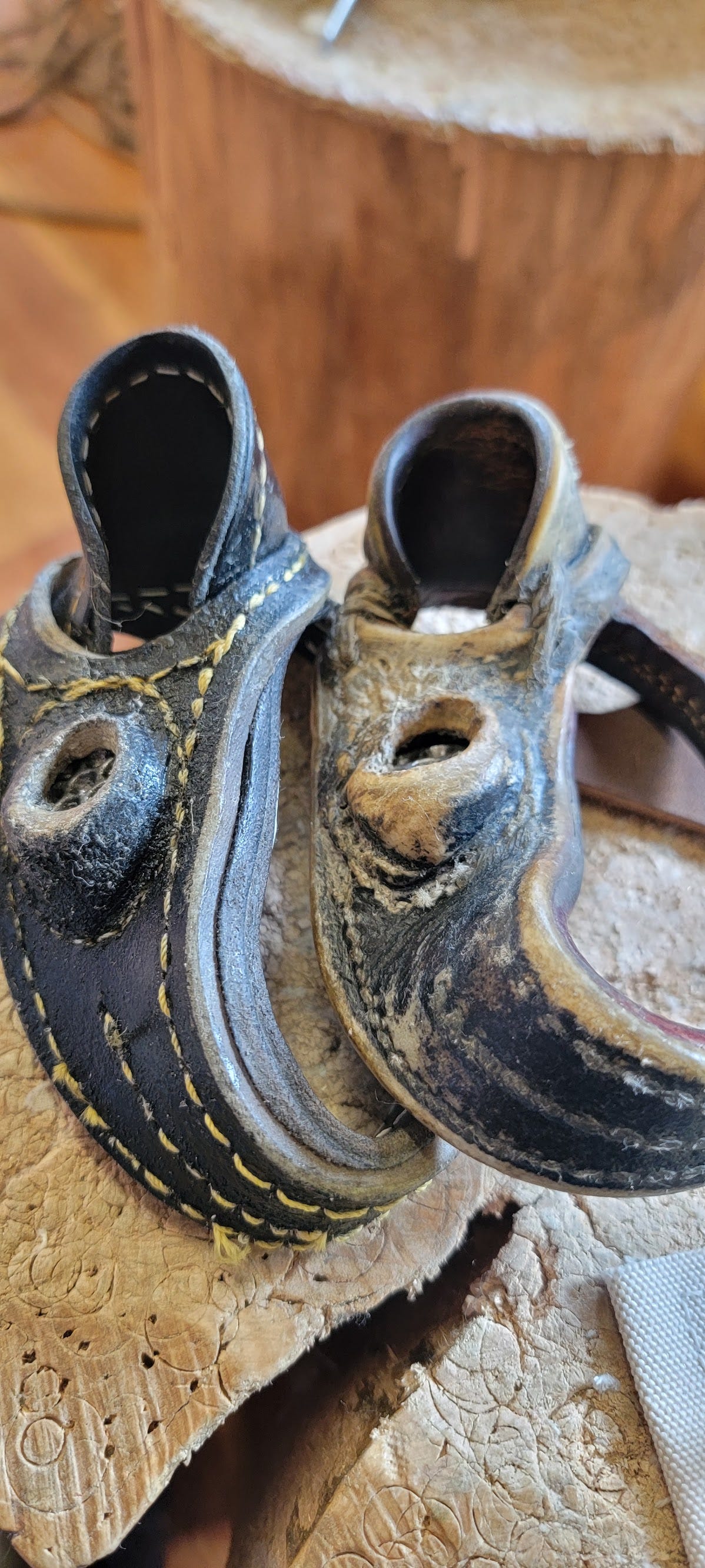 A pair of well loved leather sailmaker palms on a wooden stump covered in circular cuts. A pair of well loved leather sailmaker palms on a wooden stump covered in circular cuts.