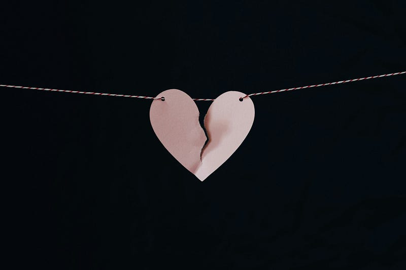 A broken paper heart hangs on a string.