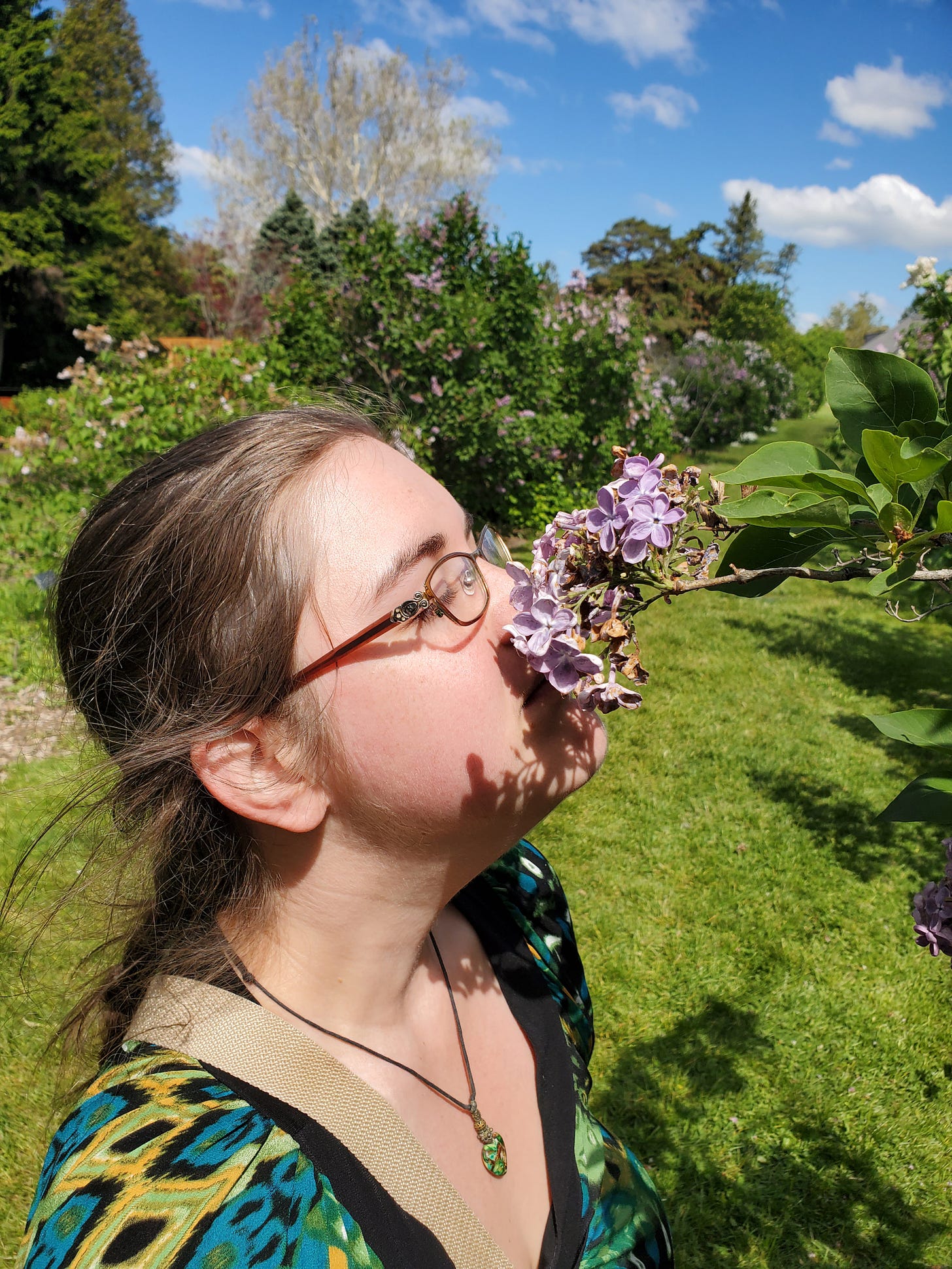 Jerrica sniffs a drooping lilac bloom.