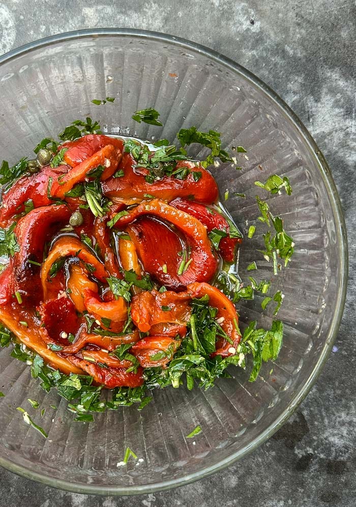 Sweet roasted red peppers marinated with garlic, herbs, and olive oil. An easy make-ahead recipe for sandwiches, salads, and snack boards. Full recipe on Shutterbean. Sweet roasted red peppers marinated with garlic, herbs, and olive oil. An easy make-ahead recipe for sandwiches, salads, and snack boards. Full recipe on Shutterbean.