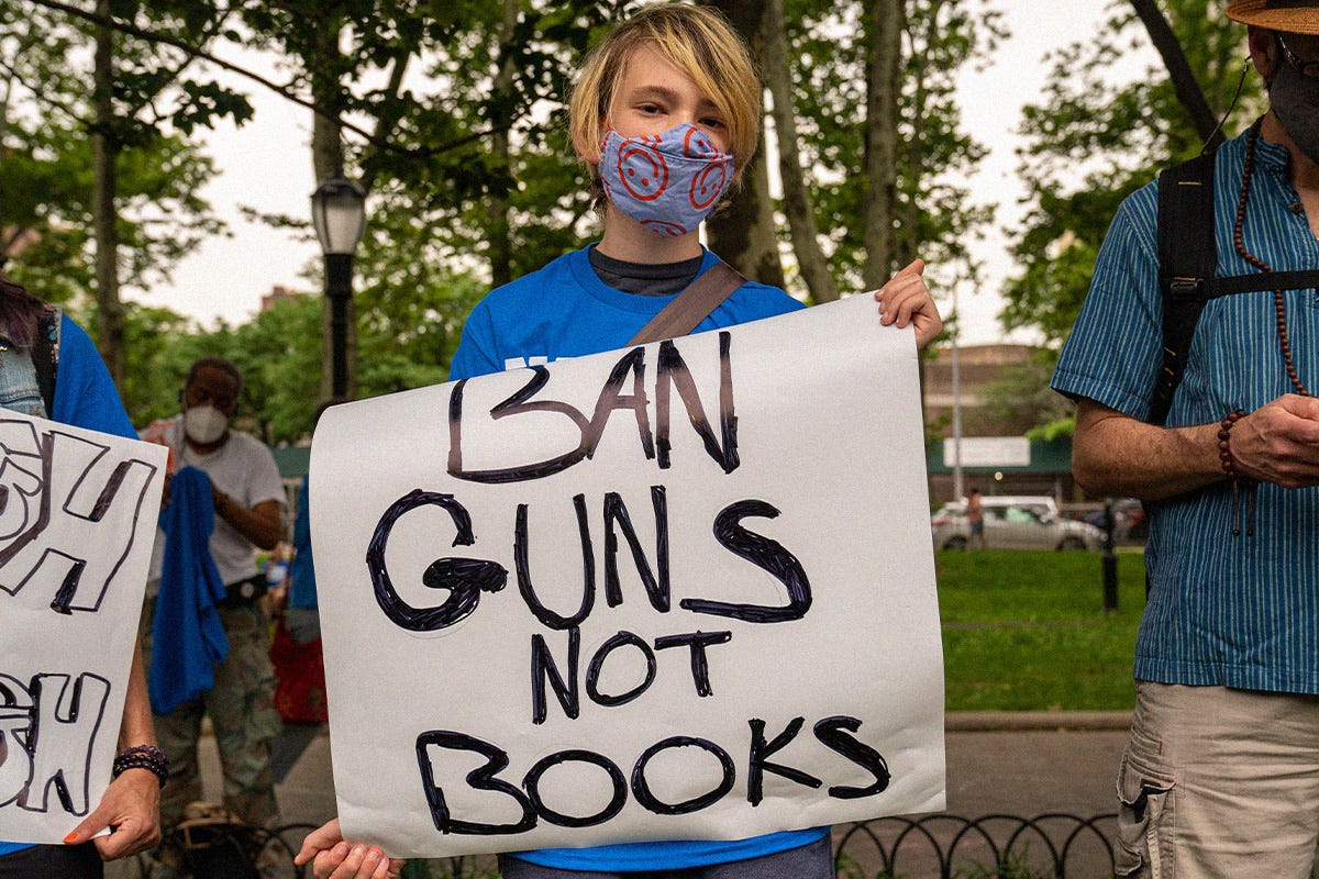 Protester takes part in the gun control protest March For Our Lives June 11, 2022 in the Brooklyn borough of New York City. They hold a sign reading "Ban guns, not books."