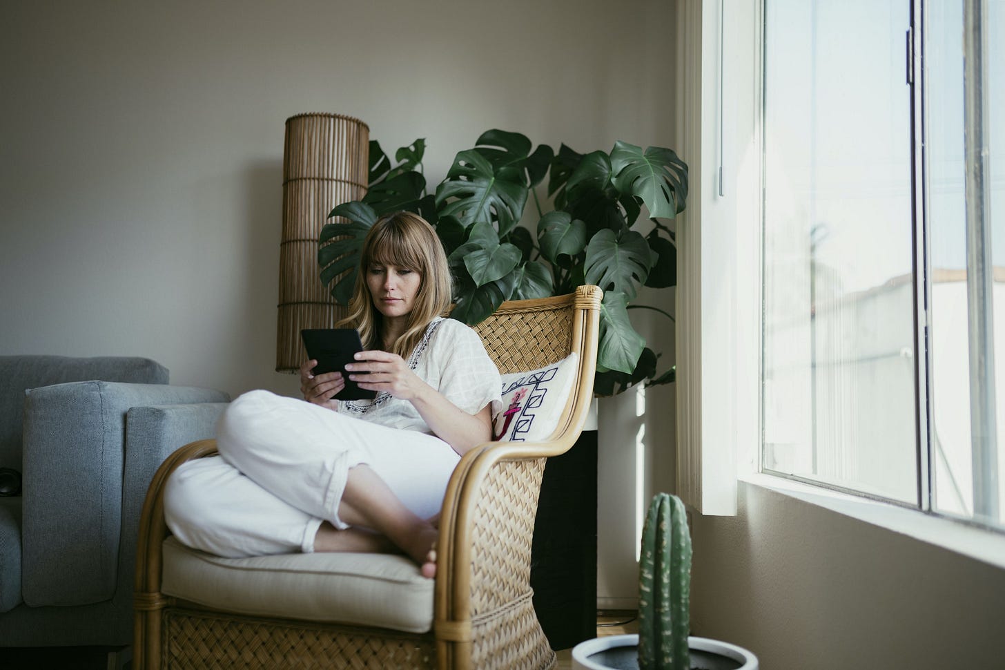 A woman sits in a chair and reads her eBook in the afternoon light. A woman sits in a chair and reads her eBook in the afternoon light.