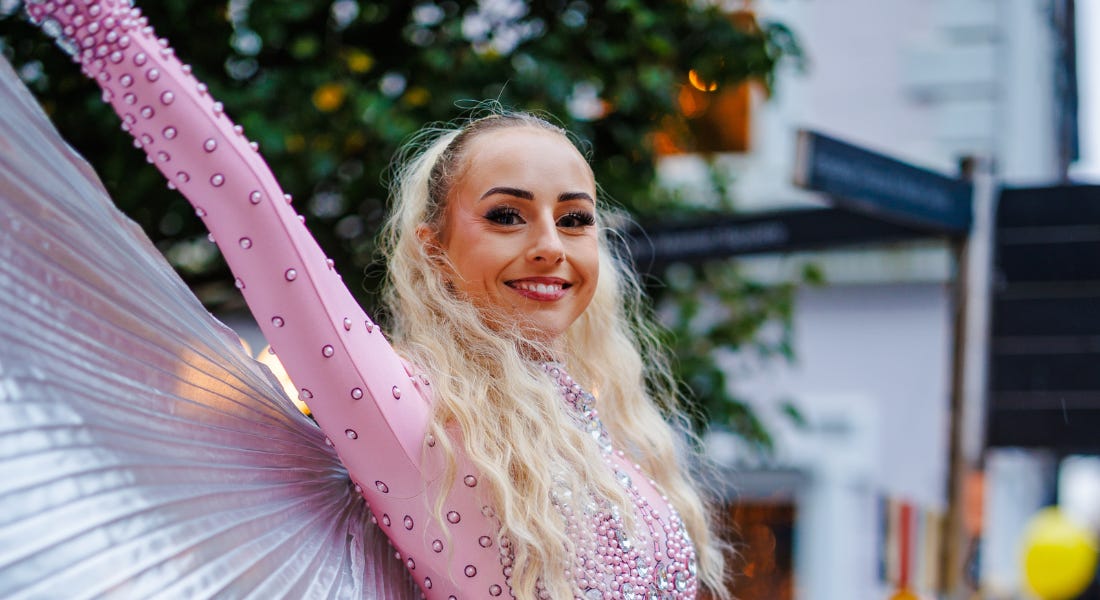 A woman with blonde hair and a pink outfit with her arm in the air A woman with blonde hair and a pink outfit with her arm in the air