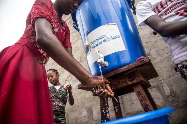 Woman at water tank washing hands 