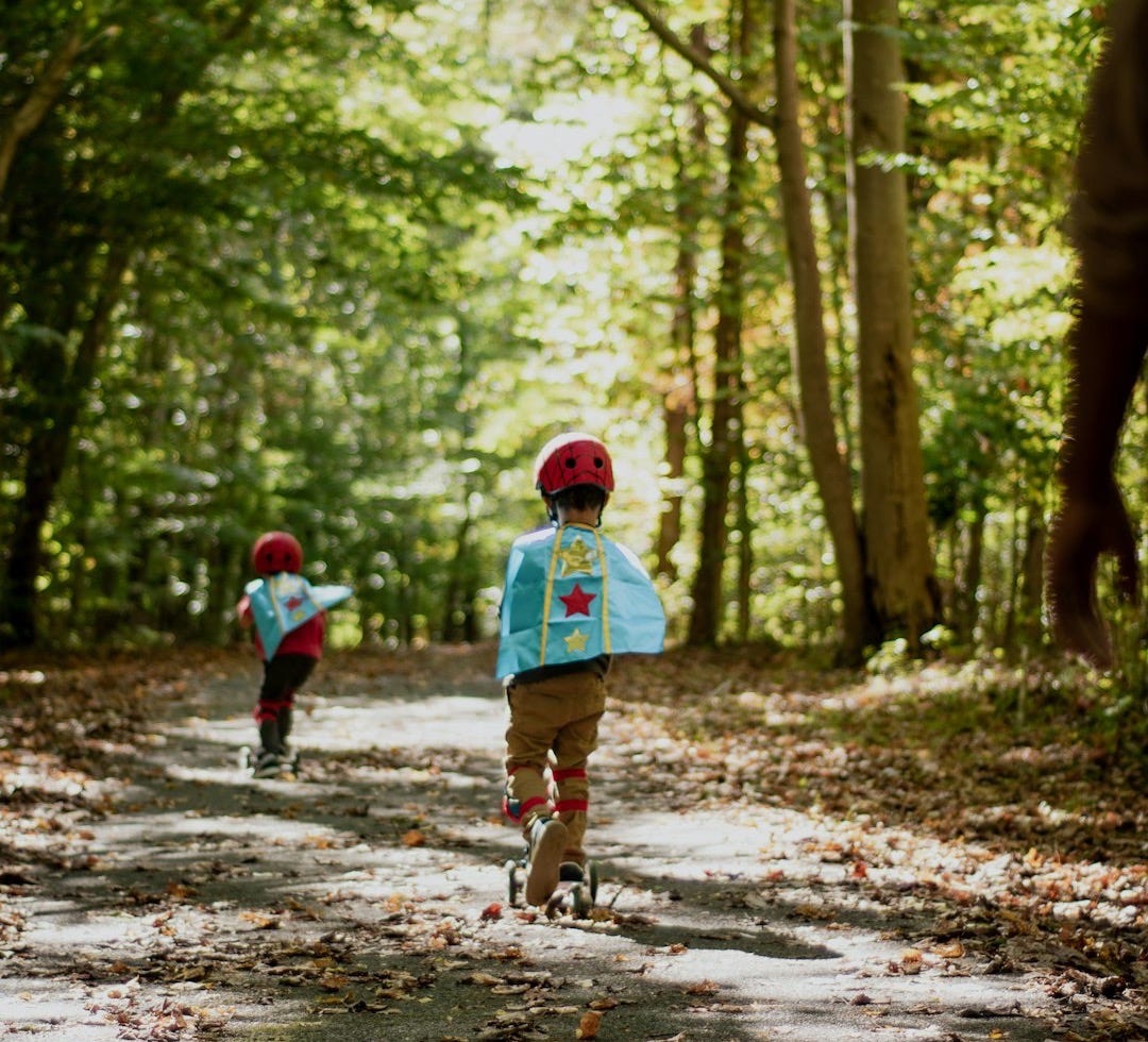 a couple of kids riding bikes down a dirt road a couple of kids riding bikes down a dirt road