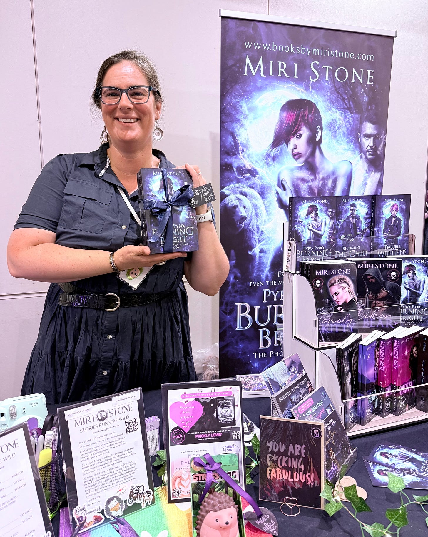 Miri Stone standing with her special editions of the Phoenix Crew behind her author table at Meet Me in the Mountains book signing 2026