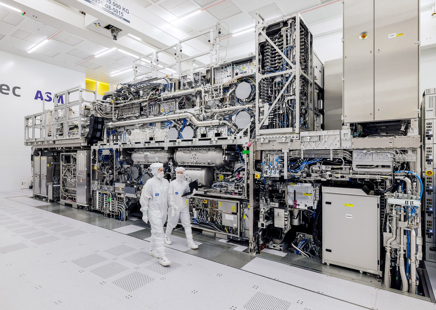 Two ASML workers walk past the High NA EUV machine in Veldhoven