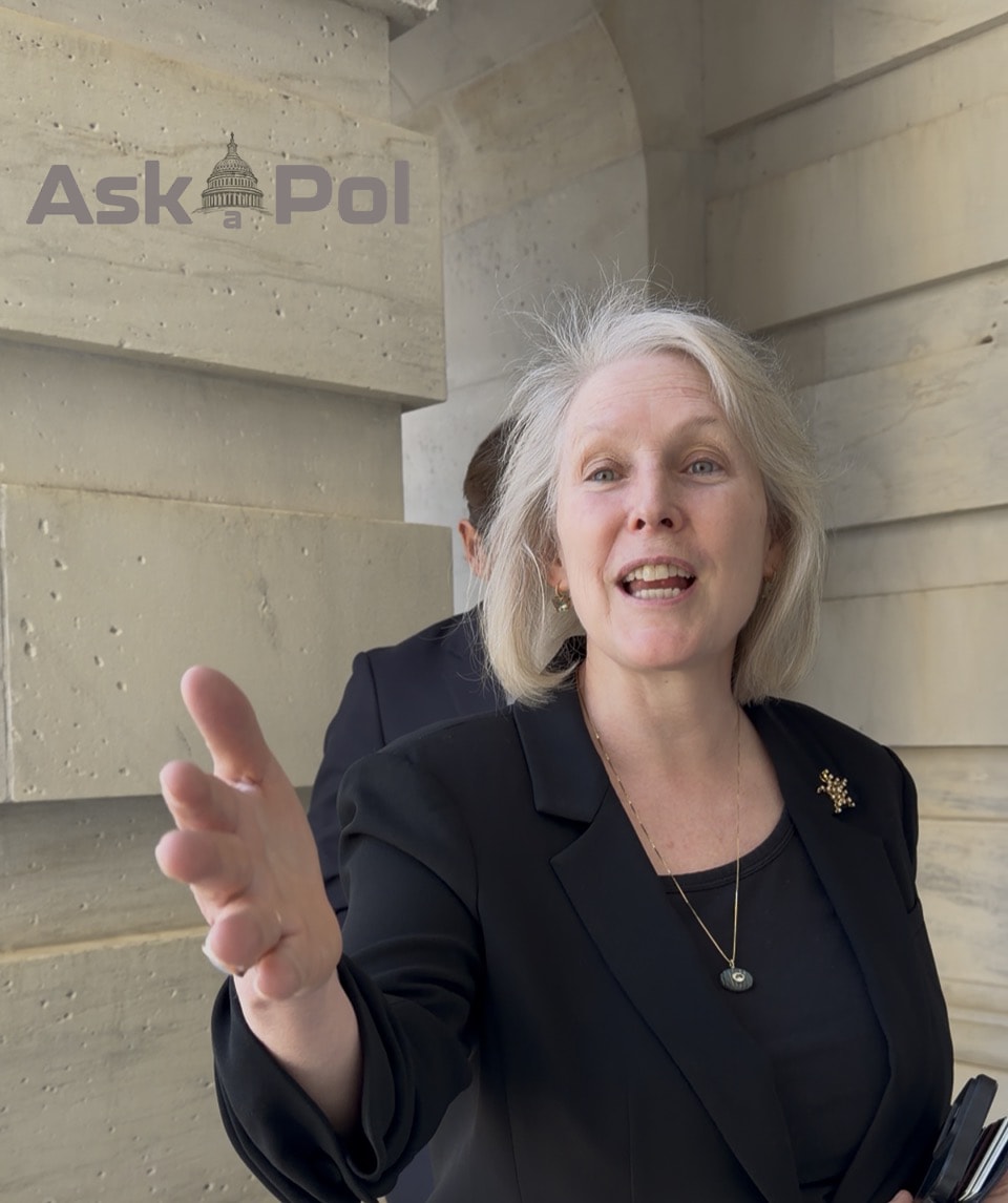 A female in a dark suit speaks while holding out her outstretched hand. Photo Matt Laslo for © www.askapoluaps.com A female in a dark suit speaks while holding out her outstretched hand. Photo Matt Laslo for © www.askapoluaps.com