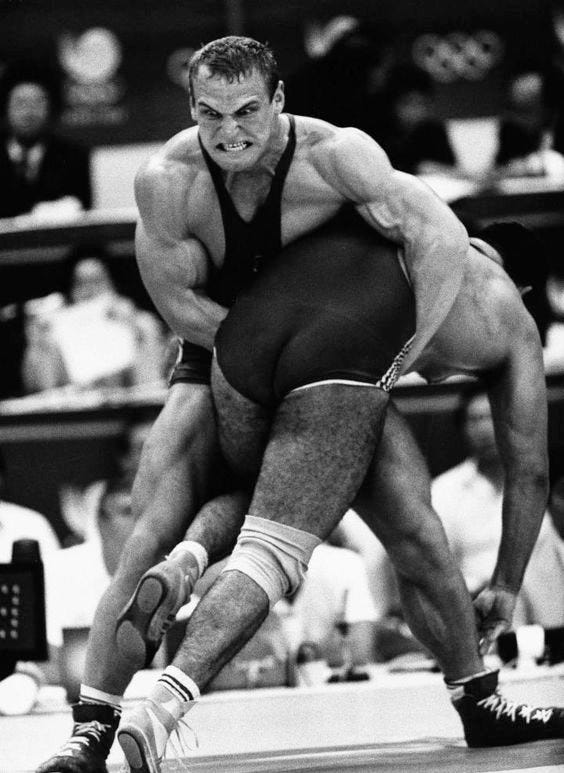This may contain: two men wrestling in an arena with people watching