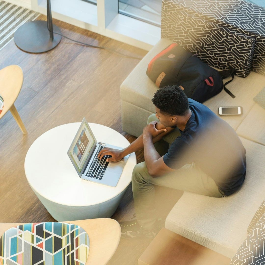 man sitting on couch using MacBook man sitting on couch using MacBook