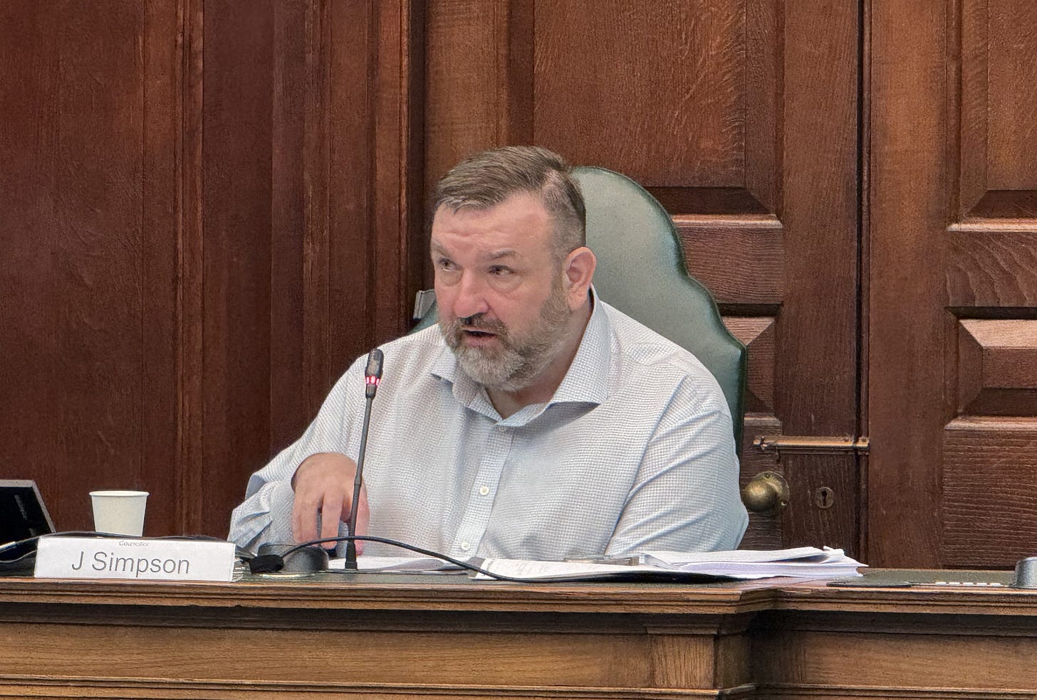 Councillor Jonathan Simpson sitting in council chamber at Camden Town Hall.