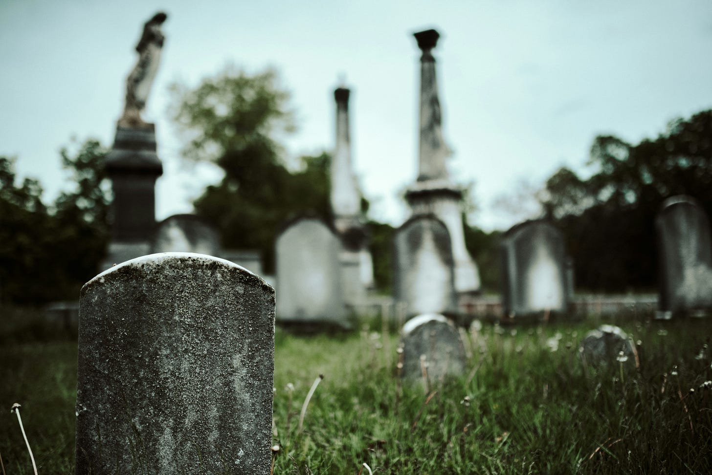 closeup image of a white gravestone with cemetary in blurred background