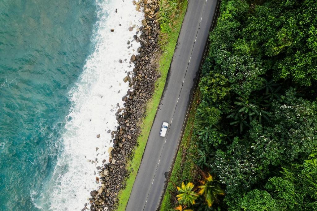 aerial view of a car driving along a coastal road aerial view of a car driving along a coastal road