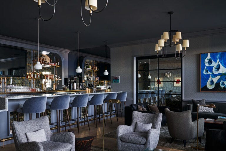 View of The Salon facing seating and the empty bar with lights off. View of The Salon facing seating and the empty bar with lights off.
