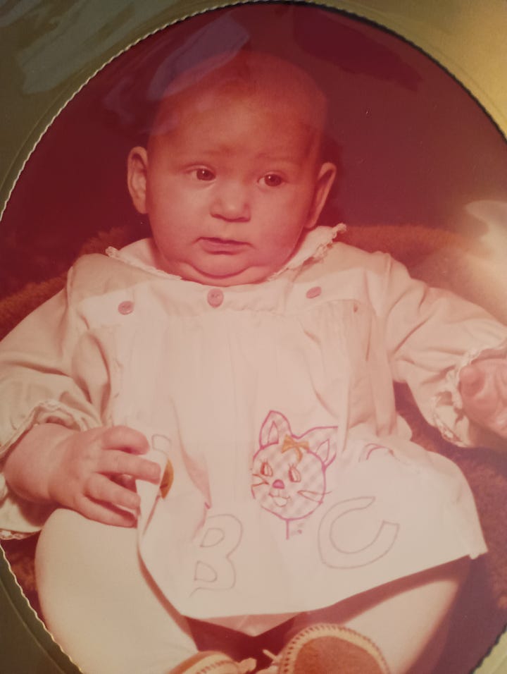 A baby side-eyeing a green pin that says I never harrassed anyone I didn't like