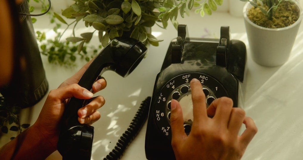 person holding black rotary telephone person holding black rotary telephone
