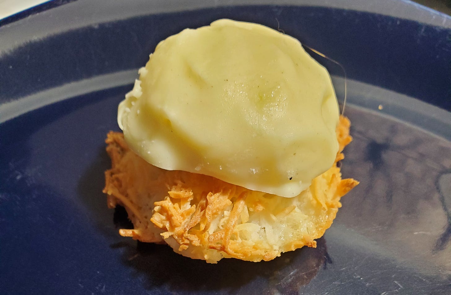 A white chocolate dome sits on top of a coconut macaroon.