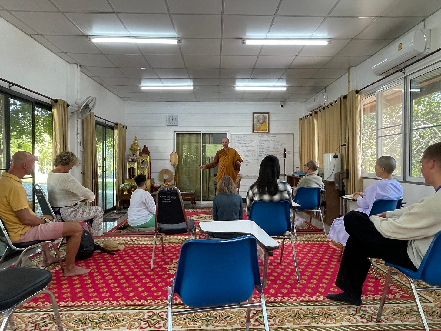 monk teaching dhamma, mindfulness  and vipassana in a classroom inside temple with many yogis