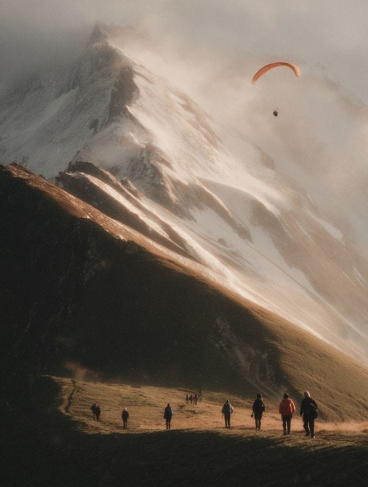 This may contain: several people are walking on the side of a mountain with a parachute in the sky
